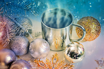 Image showing Metal mug with hot steaming coffee, Christmas balls, Christmas tree.