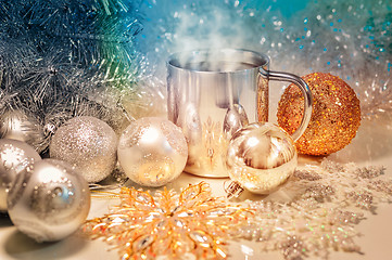 Image showing Metal mug with hot steaming coffee, Christmas balls, Christmas tree.