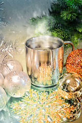 Image showing Metal mug with hot steaming coffee, Christmas balls, Christmas tree.