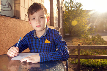 Image showing Boy doing homework outdoors