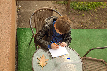 Image showing Boy is doing homework outdoors