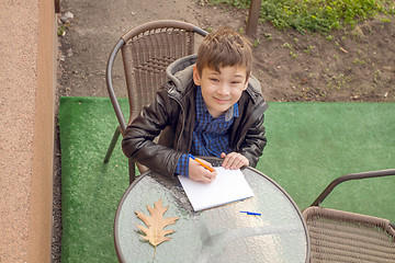 Image showing Boy is doing homework outdoors