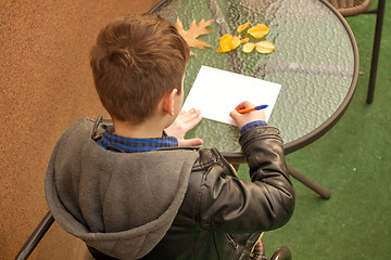 Image showing Boy is doing homework outdoors