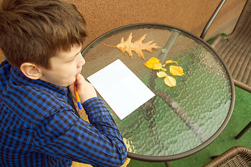 Image showing Boy is doing homework outdoors