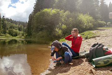 Image showing Mother and son is sitting by the lake