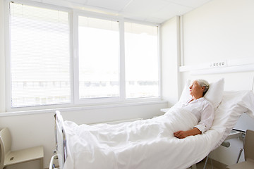 Image showing sad senior woman lying on bed at hospital ward