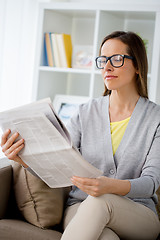 Image showing woman in glasses reading newspaper at home