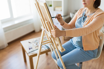 Image showing artist with easel and brush painting at art studio