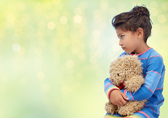 Image showing sad little girl with teddy bear over green lights