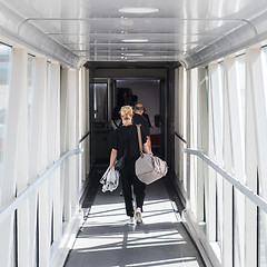 Image showing Female passenger carrying the hand luggage bag, walking the airplane boarding corridor.