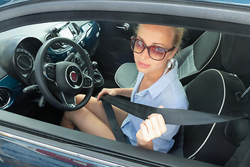 Image showing Safety first. Beautiful blonde caucasian lady fastening car seat belt.