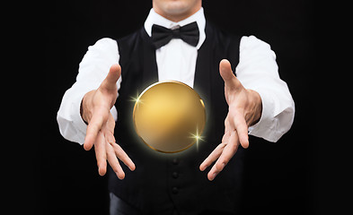 Image showing close up of magician with golden coin over black