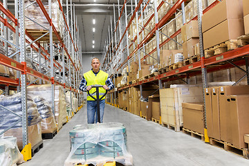 Image showing warehouse worker carrying loader with goods