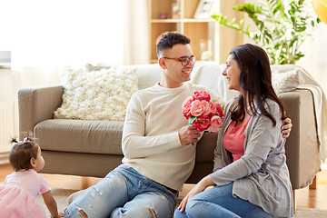 Image showing happy husband giving flowers to his wife at home