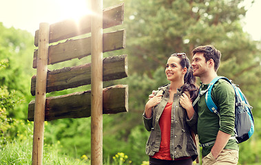 Image showing smiling couple at signpost with backpacks hiking