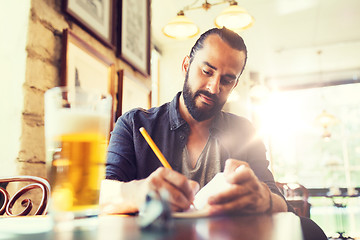 Image showing man with beer writing to notebook at bar or pub