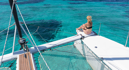 Image showing Woman relaxing on a summer sailing cruise, sitting on a luxury catamaran in picture perfect turquoise blue lagoon near Spargi island in Maddalena Archipelago, Sardinia, Italy.