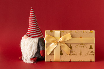 Image showing Christmas decoration with a gnome and a gift box on red backgrou