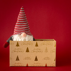 Image showing Christmas decoration with a gnome and a gift box on red backgrou