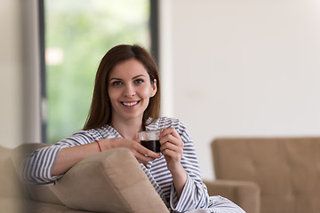 Image showing young woman in a bathrobe enjoying morning coffee