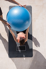 Image showing woman and personal trainer doing exercise with pilates ball