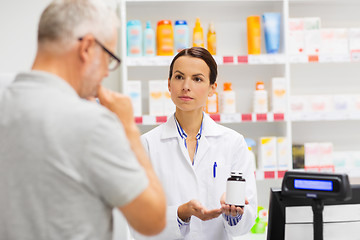 Image showing apothecary showing drug to senior man at pharmacy