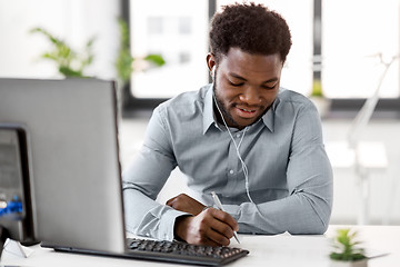 Image showing businessman with earphones and papers at office