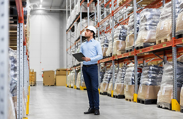 Image showing businessman in helmet with clipboard at warehouse