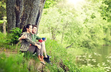Image showing happy couple with cups drinking tea in nature