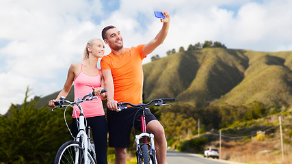 Image showing couple with bicycles taking selfie by smartphone