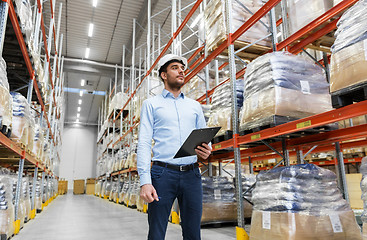 Image showing businessman in helmet with clipboard at warehouse