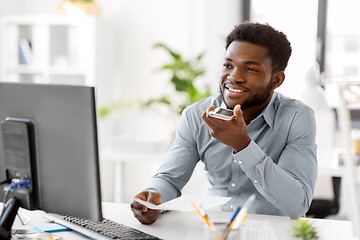 Image showing businessman records voice by smartphone at office