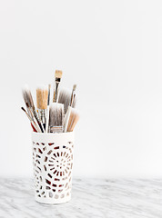 Image showing Paintbrushes in a decorative vase on marble surface