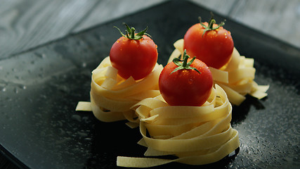 Image showing Spaghetti rolled in balls with tomatoes