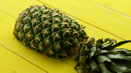 Image showing Half of pineapple on yellow wood