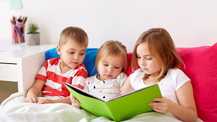 Image showing little kids reading book in bed at home