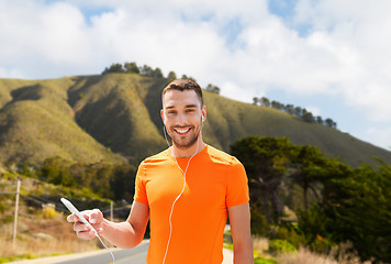 Image showing man with smartphone and earphones over hills