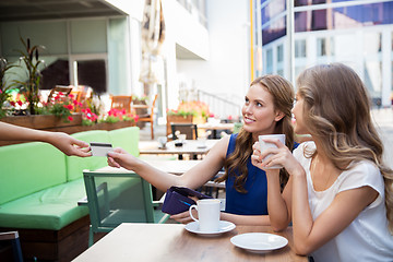 Image showing young women paying for coffee at street cafe