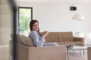 Image showing young woman in a bathrobe enjoying morning coffee