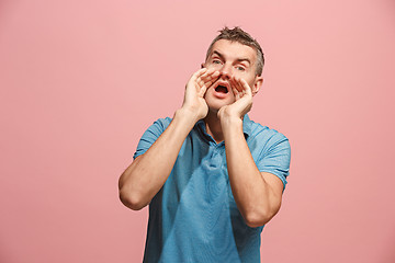 Image showing Isolated on pink young casual man shouting at studio