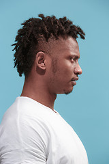 Image showing The surprised business Afro-American man standing and looking blue background. Profile view.