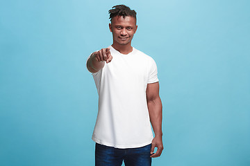 Image showing The happy afro-american businessman point you and want you, half length closeup portrait on blue background.