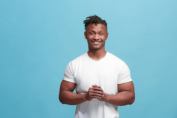 Image showing The happy afro-american business man standing and smiling against blue background.