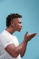 Image showing Portrait of attractive Afro-American man with air kiss isolated over blue background