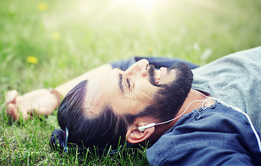 Image showing man with earphones listening to music on grass