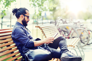 Image showing man with tablet pc sitting on city street bench