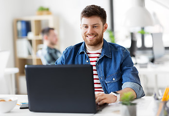 Image showing smiling creative man with laptop working at office