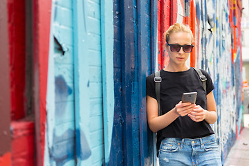 Image showing Woman using smartphone against colorful graffiti wall in New York city, USA.