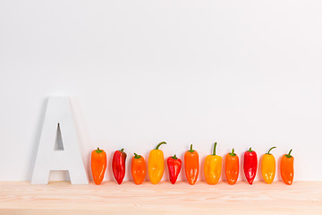 Image showing Colorful peppers and letter A on wooden surface