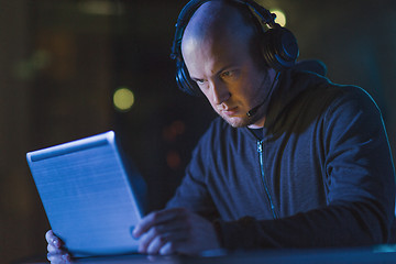 Image showing hacker in headset typing on laptop in dark room